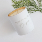 The Forever Loved Custom Engraved Candle placed on a mantel, radiating comforting vanilla and woody undertones for weddings or anniversaries.